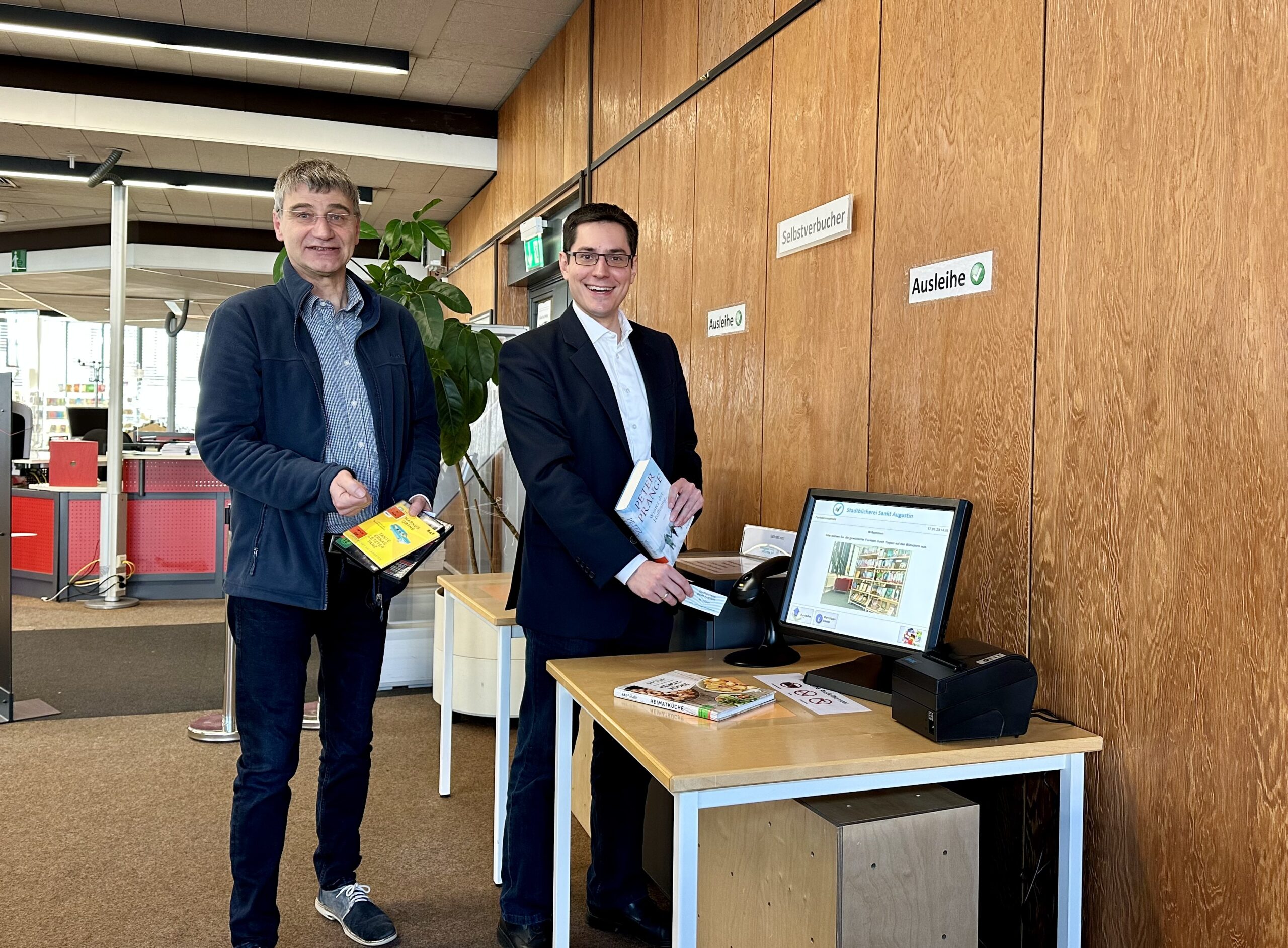 Medienausleihe am Selbstbedienungsplatz – Bürgermeister Max Leitterstorf testet den Selbstverbucher, unterstützt von Bibliotheksleiter Peter Schulte-Nölke.